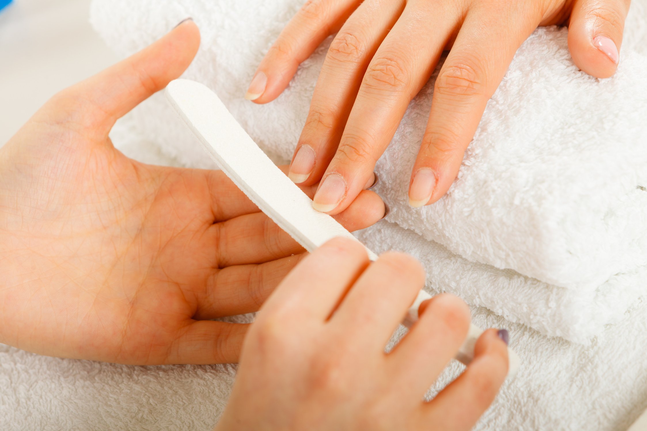 Woman getting manicure done file nails